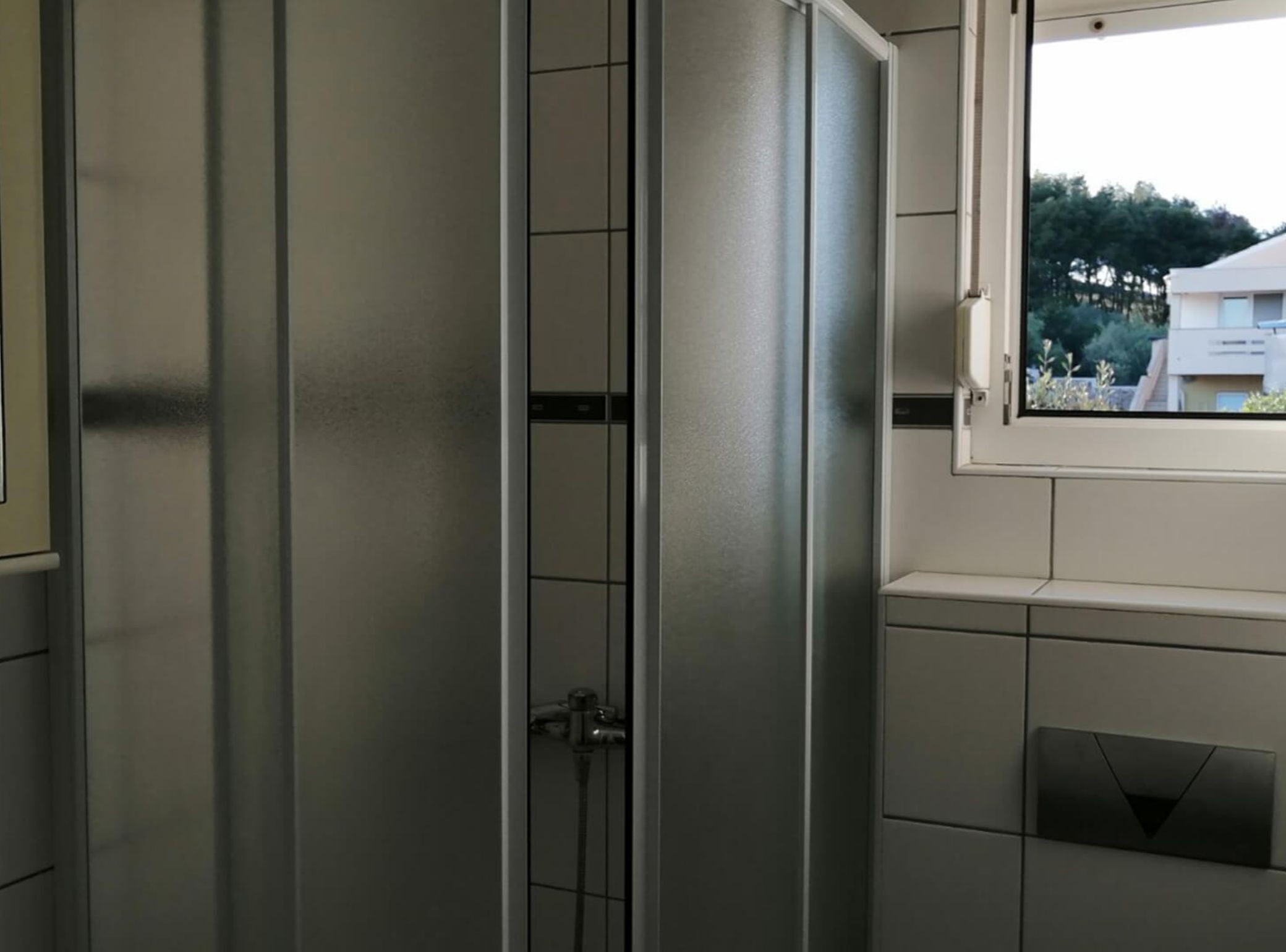 A bathroom with a shower, a window, and a towel rack.