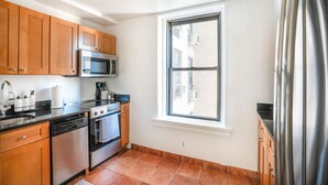 A compact kitchen with wooden cabinets, a stainless steel refrigerator, a microwave, an oven, and a dishwasher. - Upper west side 3 bedroom retreat (New York)