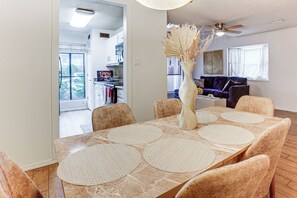 A dining area with a table set for six, a vase with dried plants, and a view into the kitchen and living room. - 5 Mi to Westchase District: Houston Extended Stay (Houston)