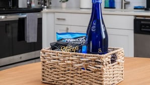 Een keuken met witte kasten, een magnetron, een koffiezetapparaat en een raam met blauwe jaloezieën.