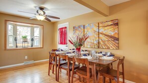 A dining area with a wooden table set for six, six chairs, a ceiling fan, and a window with a view of the outdoors. - Gather Family! Home w/ Fenced Yard in Wheat Ridge (Wheat Ridge)