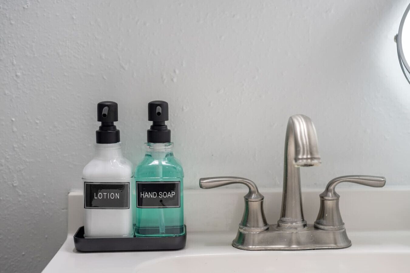 Un lavabo de salle de bain avec deux flacons de lotion et de savon pour les mains, placés sur un plateau.