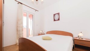 Ein Schlafzimmer mit einem hölzernen Bett, einem Nachttisch mit Lampe, einer Holzkommode und einem gerahmten Bild an der Wand.