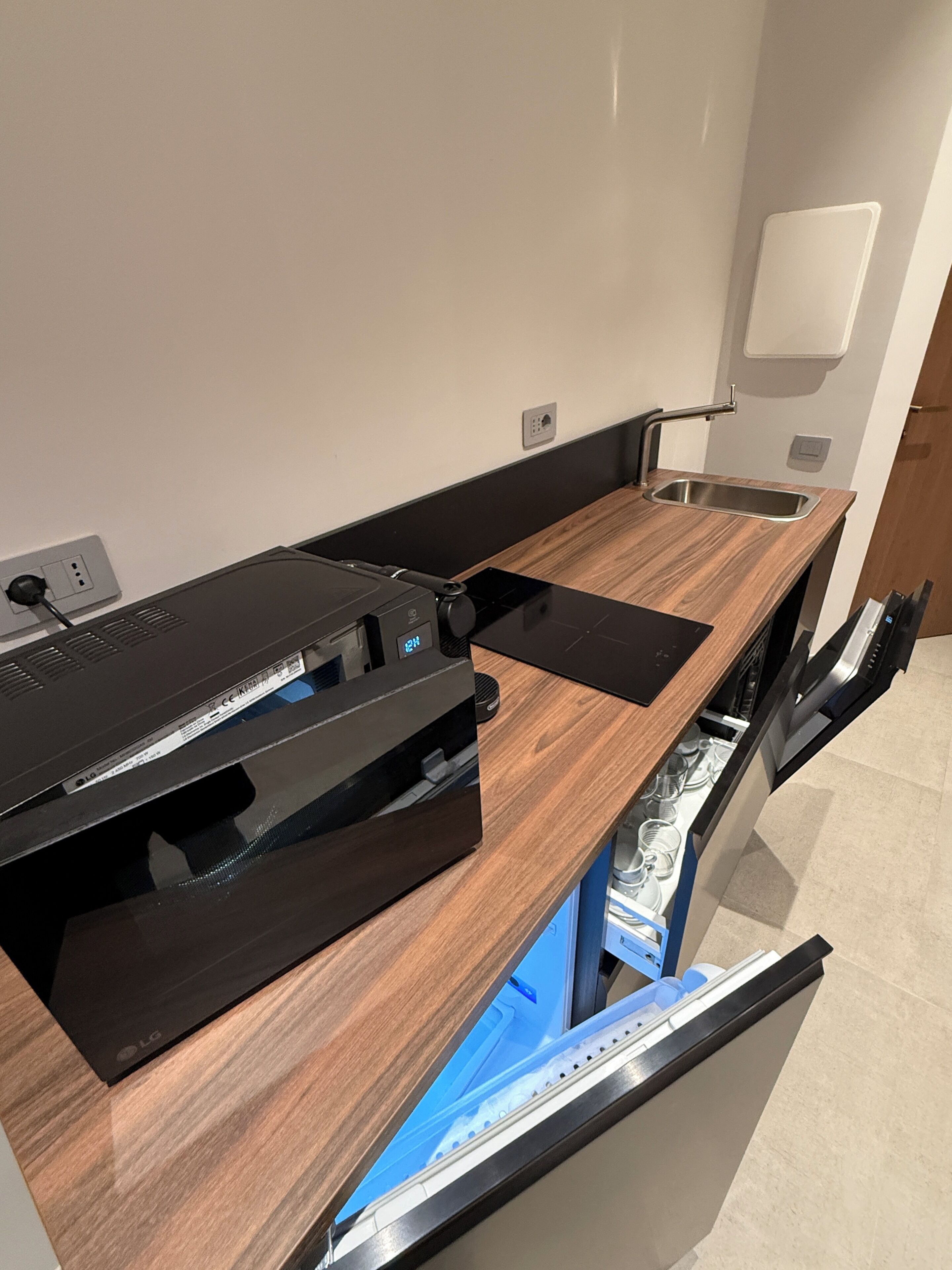 A modern kitchen with a built-in dishwasher, a wooden countertop, and a black appliance.