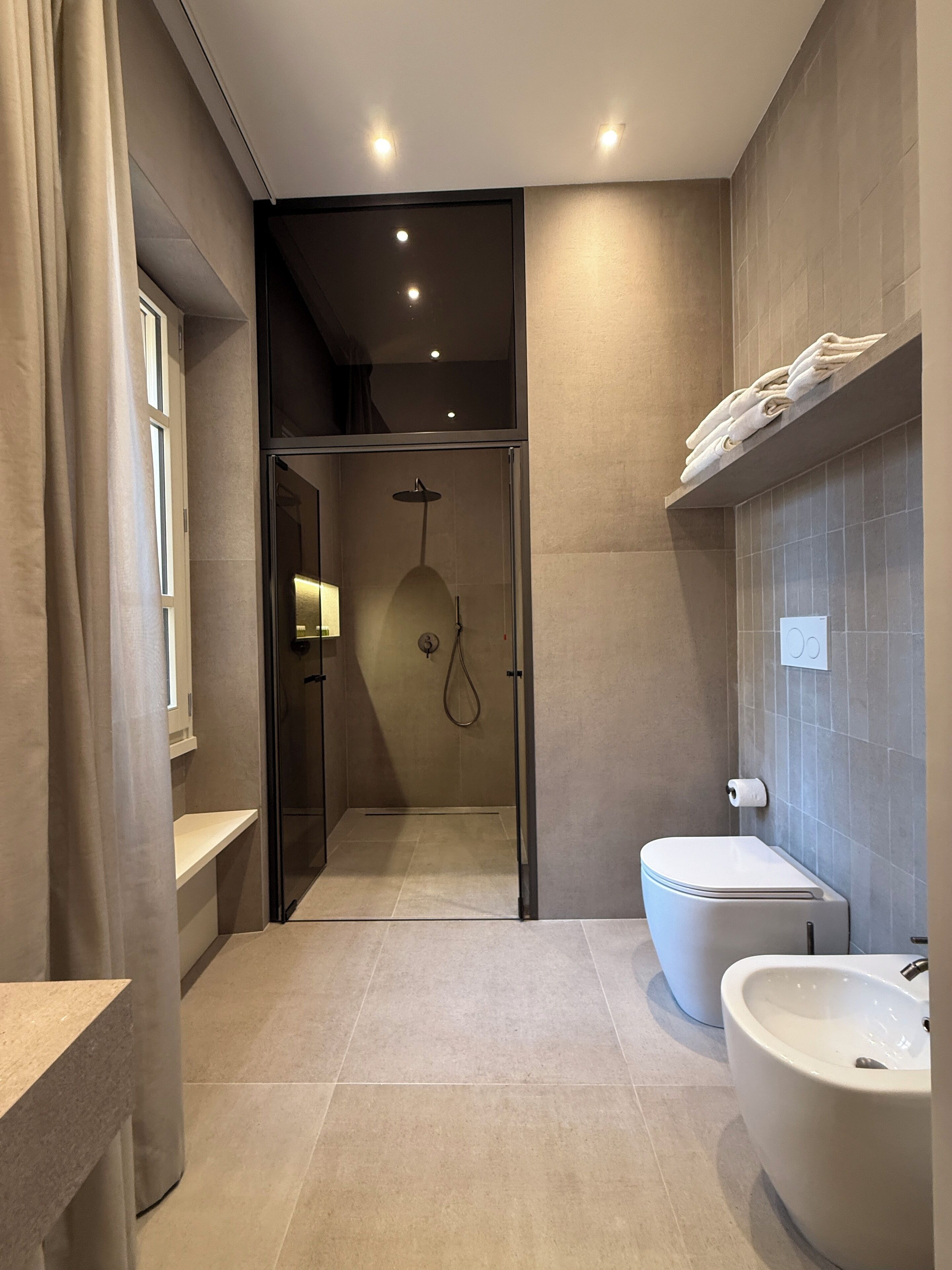 Ein modernes Badezimmer mit einer Glastrennwand-Dusche, einer freistehenden Badewanne und einer Toilette.