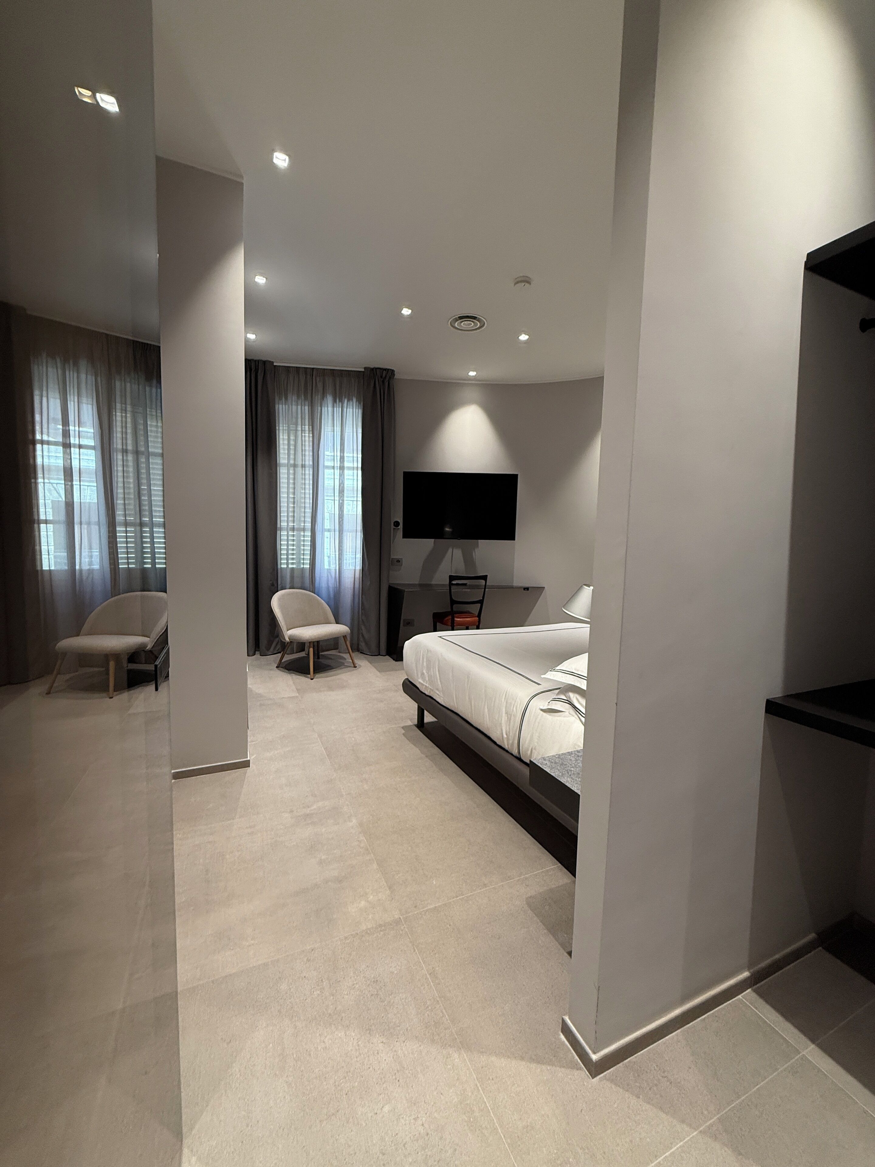 Une chambre d’hôtel moderne équipée d’un lit, d’un bureau, d’une chaise et d’un téléviseur.
