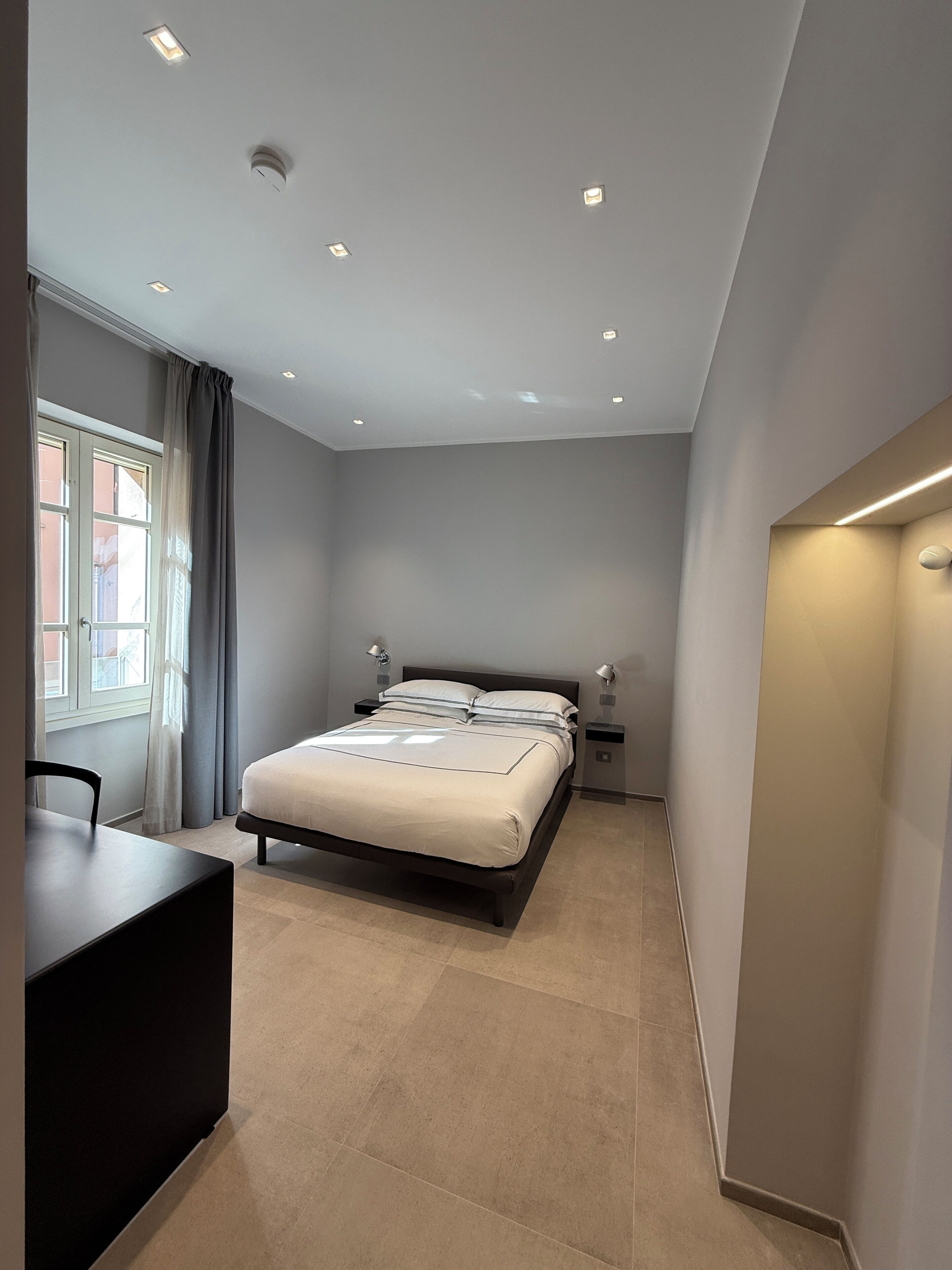 Une chambre moderne avec un lit, des tables de chevet, un bureau et une fenêtre avec des rideaux.