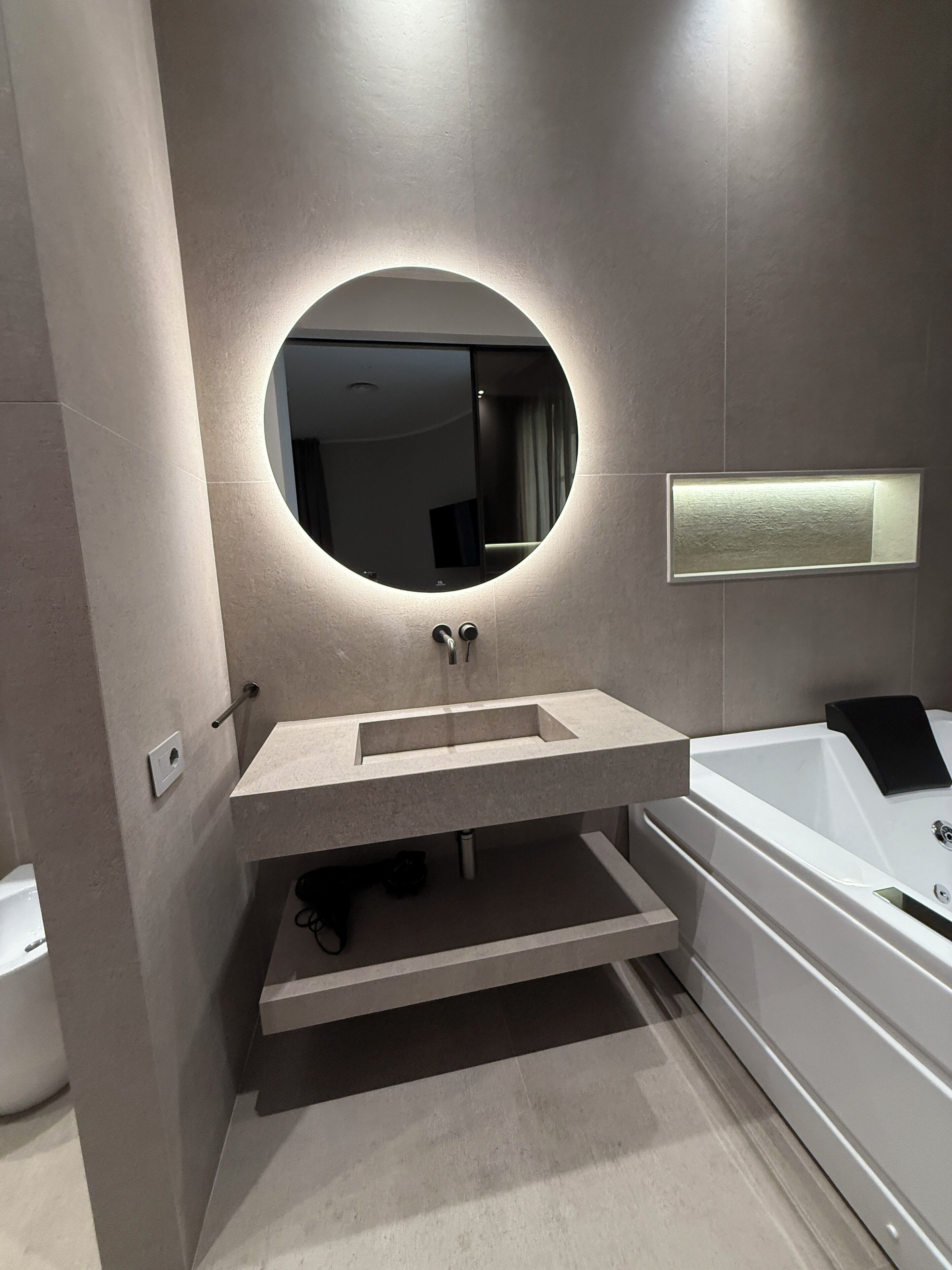 Une salle de bain moderne avec un miroir rond, un lavabo et une baignoire.