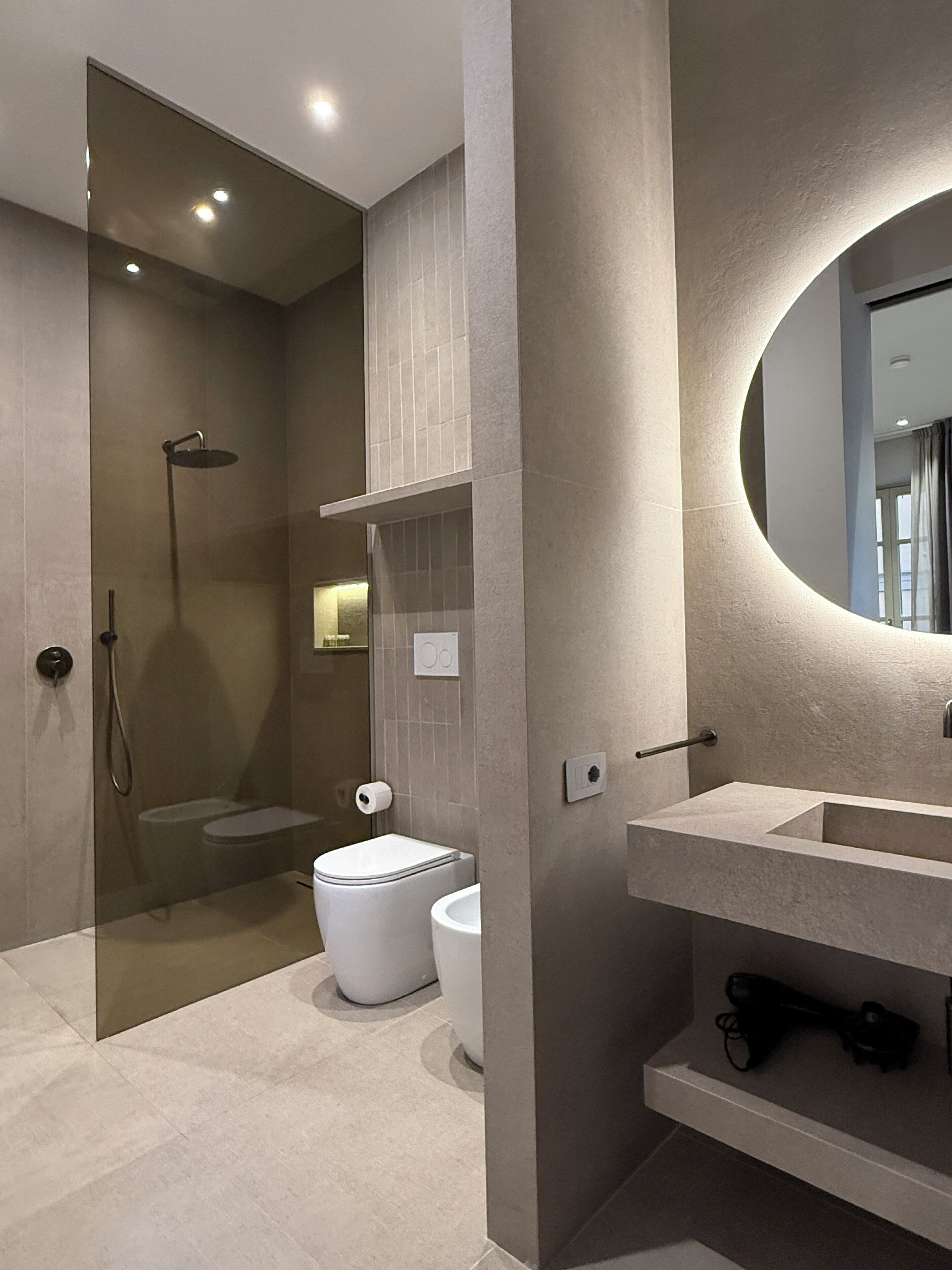 A modern bathroom with a glass-enclosed shower, a toilet, and a sink with a mirror.