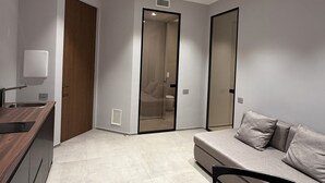 A modern, compact living space with a kitchenette, a dining area, and a seating area with a sofa and chairs. - LEOPOLDO SUITES (Cagliari)
