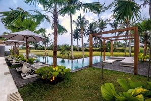 Un espace aménagé au bord de la piscine, avec des chaises longues, des parasols et une pergola en bois.