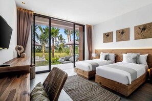 A hotel room with two beds, a desk, a TV, and a large sliding glass door leading to a garden. - Villa Florentine by BaliSuperHost (Bali)