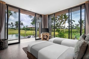 Une chambre avec un grand lit, un téléviseur posé sur un meuble en bois, et une vue sur une piscine et des palmiers.