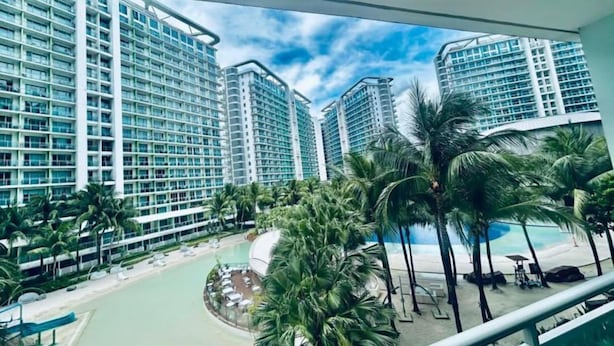 A resort with high-rise buildings, a pool area, and palm trees. - Relaxing 1BR Retreat with Balcony (Paranque)