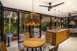 A modern interior with a dining area, a bar, and a view of a swimming pool. - Villa Alba by BaliSuperHost (Bali)