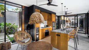 A modern kitchen with a central island, built-in appliances, and a dining area with wicker chairs. - Villa Alba by BaliSuperHost (Bali)