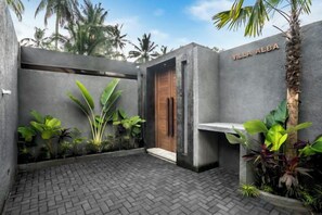 A modern outdoor area with a paved floor, a wooden door, and a bench. - Villa Alba by BaliSuperHost (Bali)
