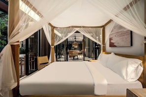 A bedroom with a canopy bed, a dining area with a table and chairs, and a view of the outdoors. - Villa Alba by BaliSuperHost (Bali)