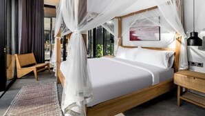 A bedroom with a canopy bed, a wooden nightstand, a chair, and a large window. - Villa Alba by BaliSuperHost (Bali)