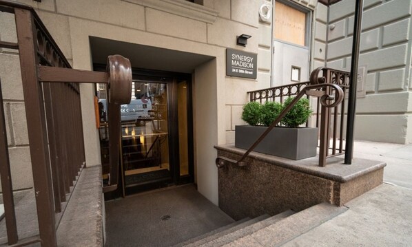 A hotel entrance with a sign reading "SYNERGY MADISON 24 E 30th Street".