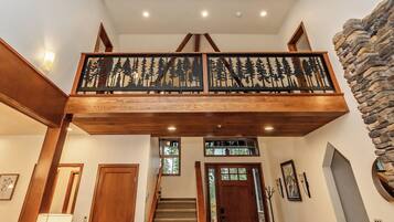 Un escalier en bois doté d’un balcon orné d’un motif représentant la silhouette d’une forêt.