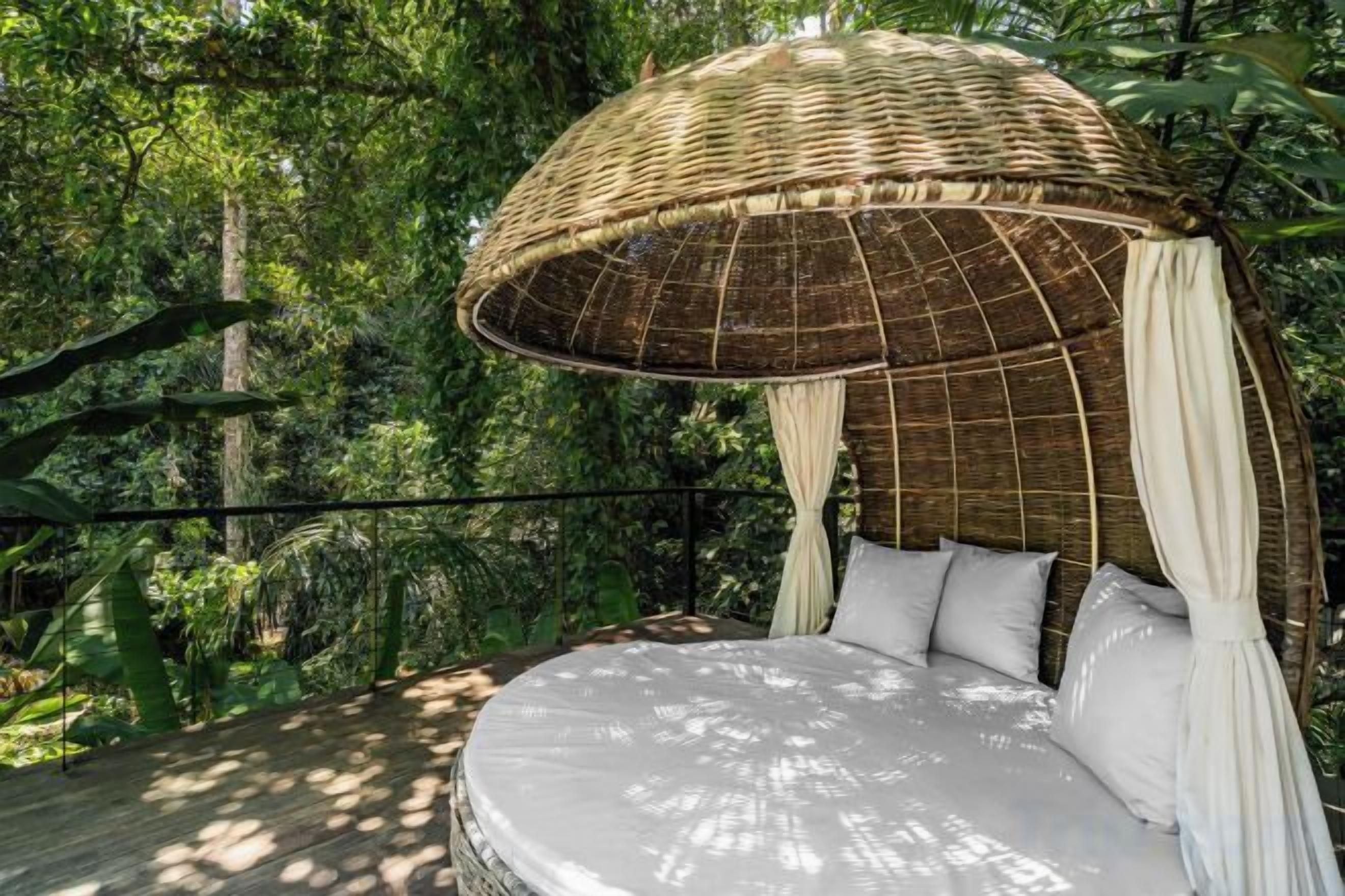 A bed with a canopy, surrounded by lush greenery.