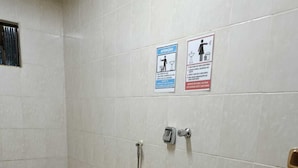 A small bathroom with a toilet, bidet, and sink. There are two signs on the wall, one indicating attention and the other for handwashing. - Namaste Camping Suite (Aruanã)