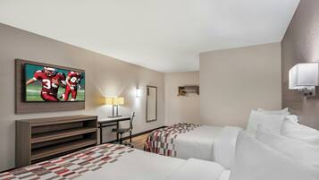 Une chambre d’hôtel avec deux lits, un bureau, une chaise, une télévision et un luminaire fixé au mur.