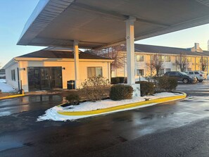 Um posto de gasolina com área coberta, um edifício com a placa de número 2808 e carros estacionados.