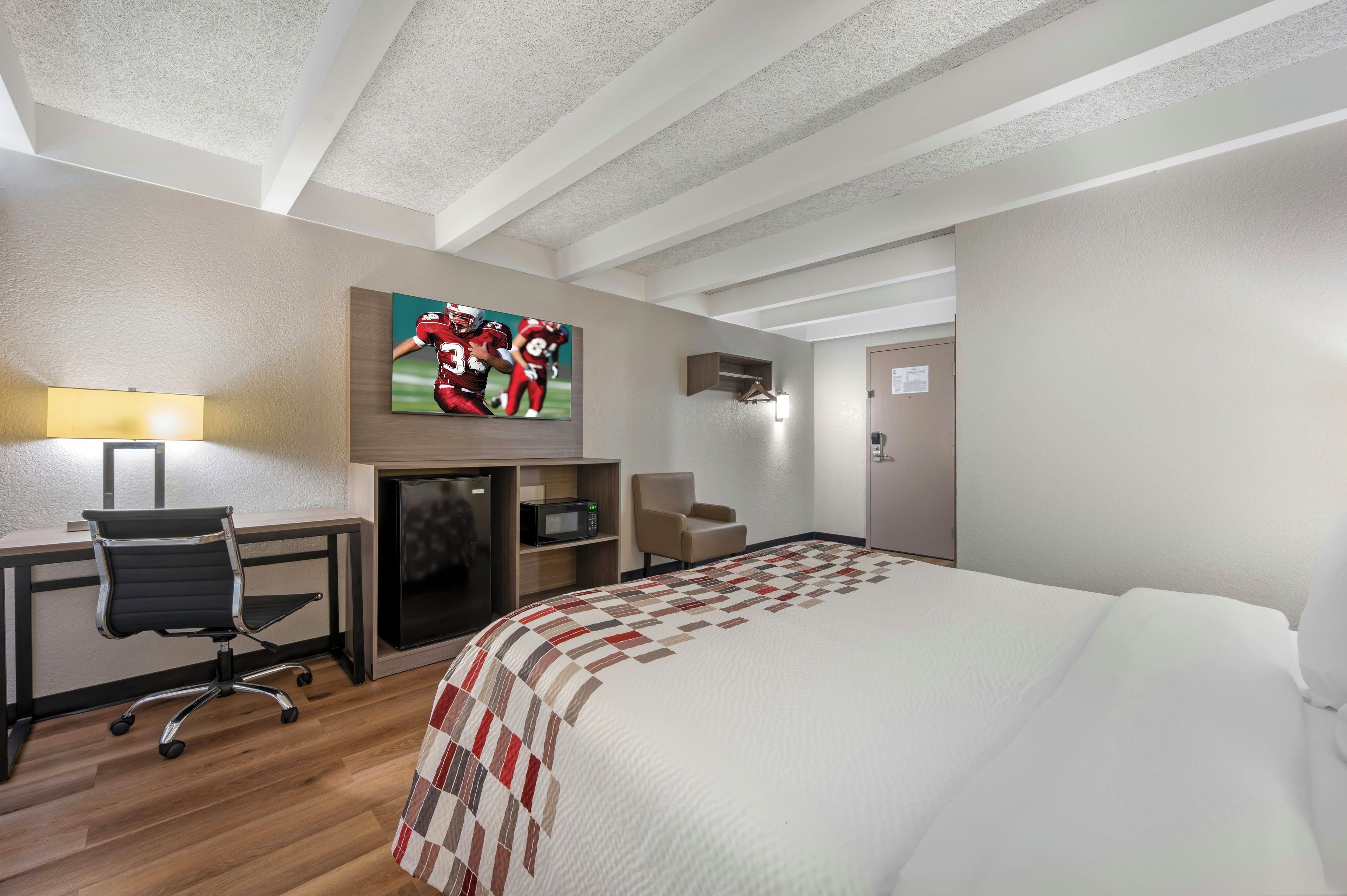 Quarto de hotel com cama, escrivaninha, cadeira, televisão e lareira.