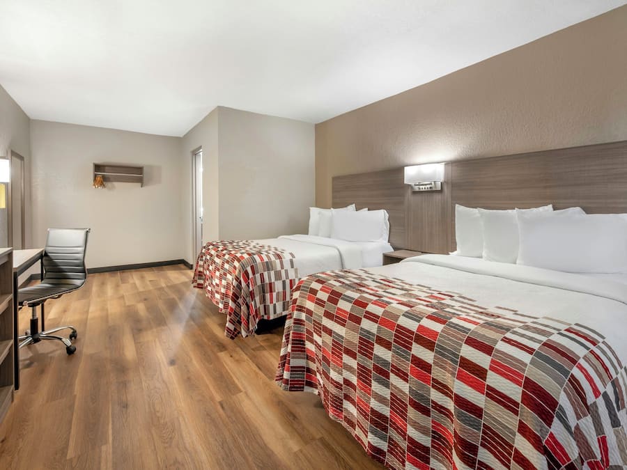 Een hotelkamer met twee bedden, een bureau en een stoel.