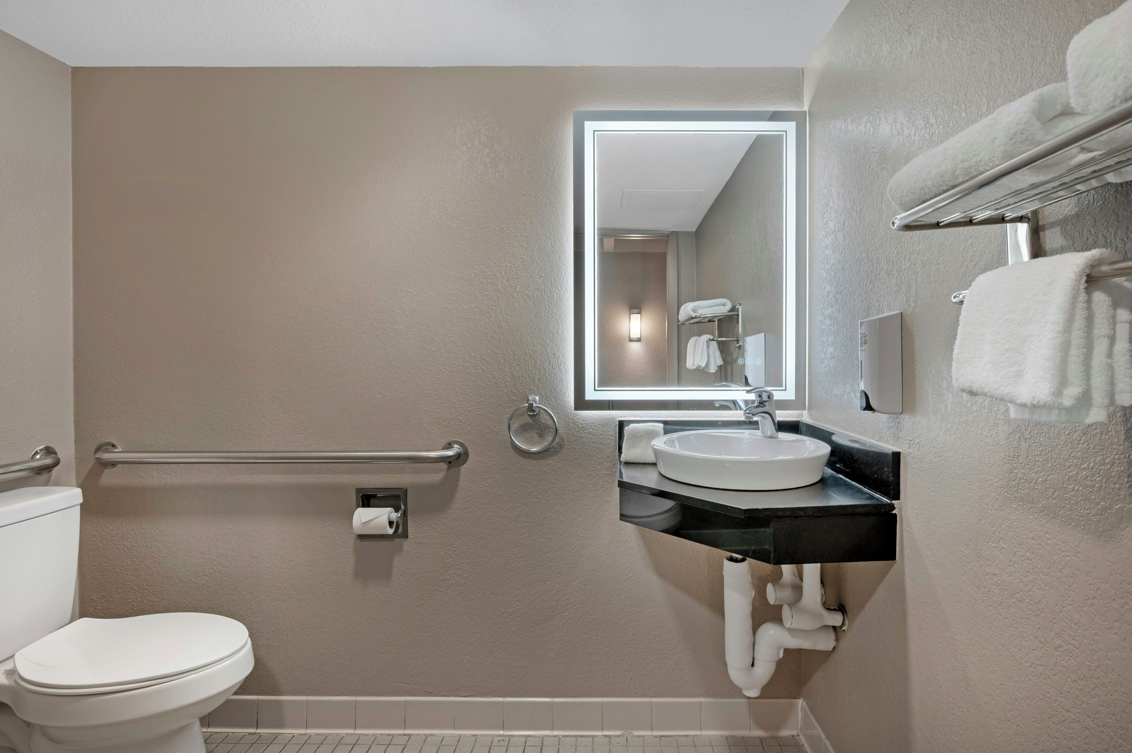 A bathroom with a toilet, a sink, a mirror, and a towel rack.