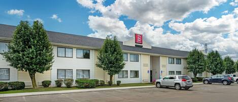 A Red Roof Inn with a parking lot and a clear sky.