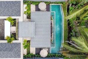 Vista aerea di un resort con piscina, area relax e vegetazione tropicale.