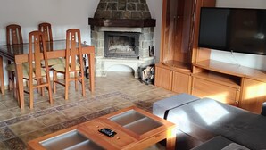 Ein Wohnzimmer mit Kamin aus Stein, Holzmöbeln und einem Flachbildfernseher.