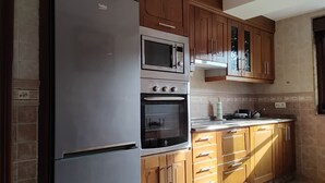 Eine Küche mit Kühlschrank, Backofen, Mikrowelle und Holzschränken.