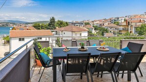 A terrace with a table and chairs overlooking a coastal town. - Lovely apartment in Okrug Gornji (Okrug Gornji)