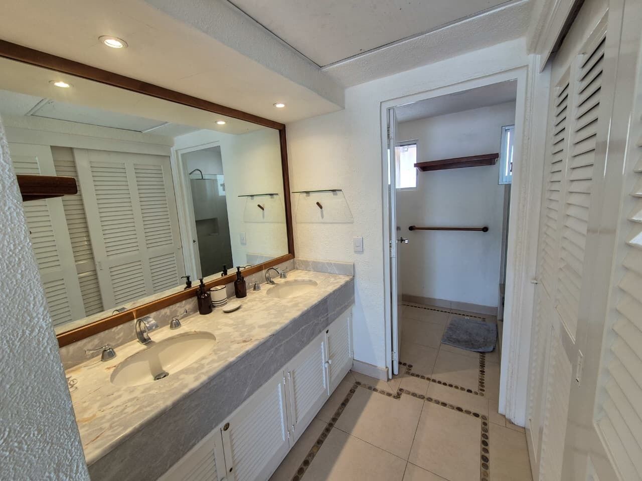 Un baño con dos lavamanos, un espejo grande y una zona de ducha.