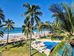 A resort with a pool, beach, and palm trees. - Condominio Iguana (Ixtapa)