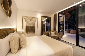 A modern bedroom with a large bed, a seating area with a chair, and a view through a glass door. - Villa Jungle Rendez Vous by BaliSuperHost (Bali)