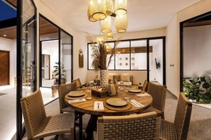 A dining area with a round table, wicker chairs, and a central vase. - Villa Jungle Rendez Vous by BaliSuperHost (Bali)