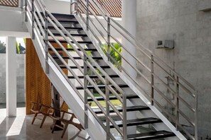 A staircase with metal railings and a glass balustrade, leading to an outdoor area with greenery. - Villa Mushika by BaliSuperHost (Bali)