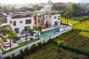 A modern two-story house with a swimming pool, surrounded by greenery and a hilly landscape. - Villa Mushika by BaliSuperHost (Bali)