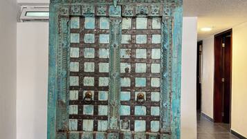 A hallway with a large, ornate door featuring a grid pattern and metal hinges.