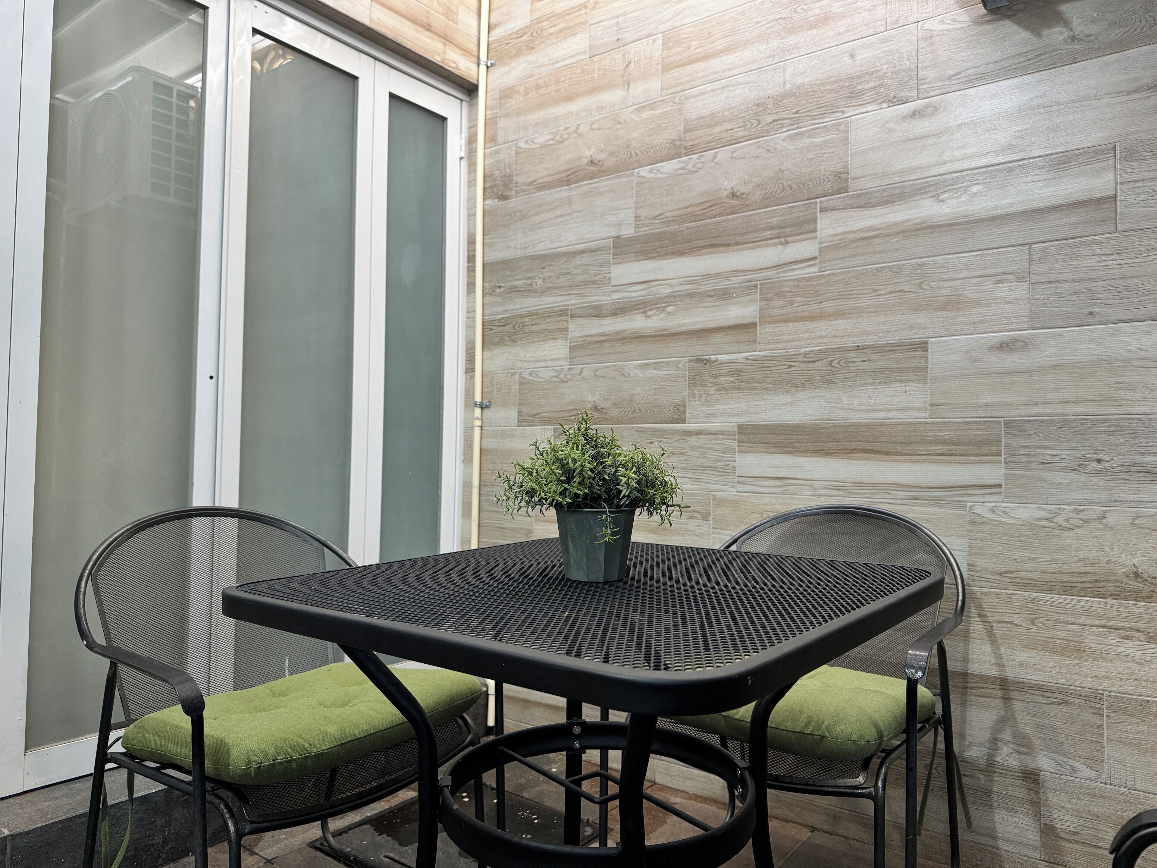 A patio area with a table and chairs, a potted plant, and a sliding glass door.