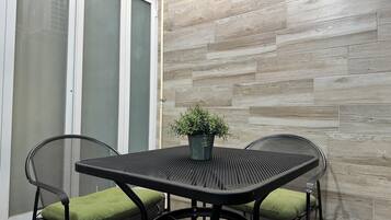 A patio area with a table and chairs, a potted plant, and a sliding glass door.