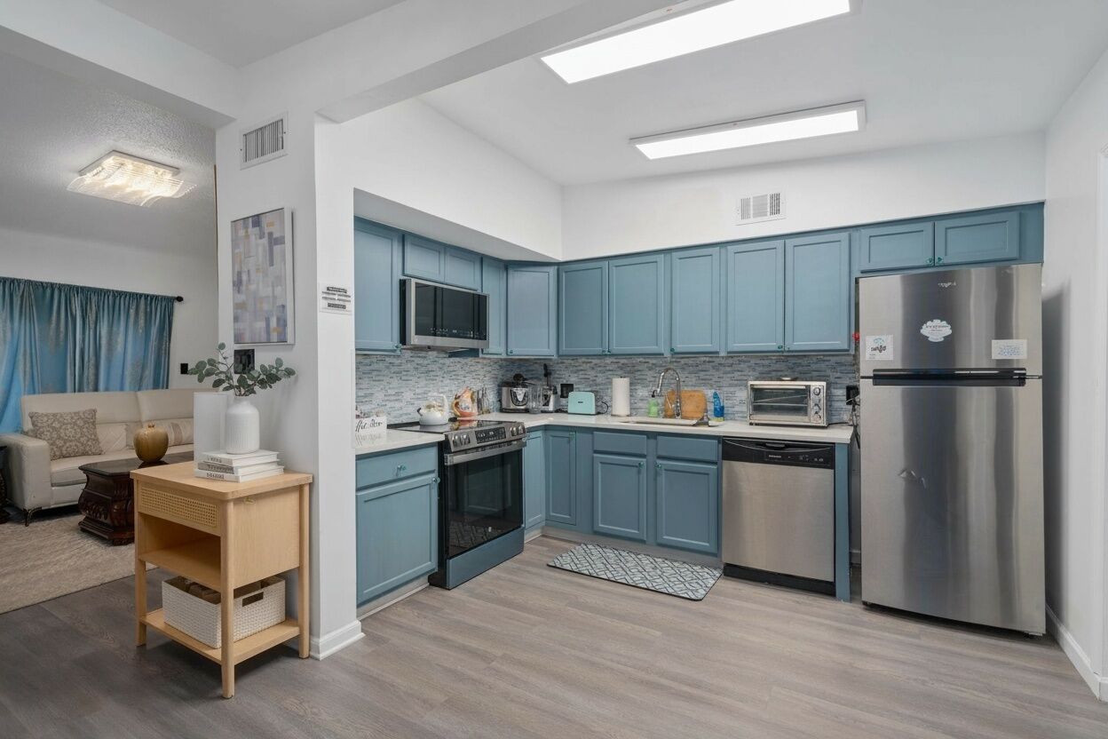 Una cocina moderna con armarios azules, electrodomésticos de acero inoxidable y una mesita de madera.