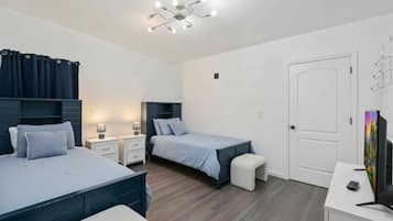 Une chambre avec deux lits, un bureau, une télévision et un luminaire au plafond.