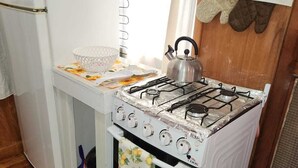 Una cocina compacta con estufa, horno y refrigerador blancos.