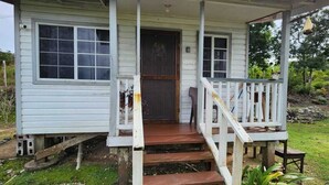 Una casa pequeña de un solo piso con un porche, una puerta principal y una escalera que conduce a la entrada.